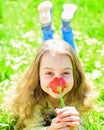 Girl lying on grass, grassplot on background. Tulip fragrance concept. Child enjoy spring sunny day while lying at