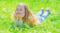 Girl lying on grass at grassplot, green background. Child enjoy spring sunny weather while lying at meadow. Springtime