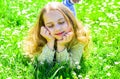 Girl lying on grass at grassplot, green background. Girl on dreamy face spend leisure outdoors. Heyday concept. Child