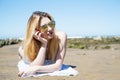 Girl lying on the sand at the beach with sunglasses heard shaped