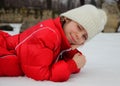 Girl lying in the snow and squinting in the bright white light