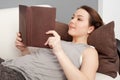 Girl lying on sofa and reading book Royalty Free Stock Photo