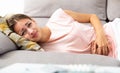 Girl lying on sofa with stomach problems