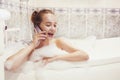 The girl is lying in the whirlpool with foam and talking on a waterproof phone. The girl relaxes and gossips. girl in the foam. Royalty Free Stock Photo