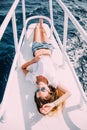 Girl lying on yacht deck. Smiling lady in swimsuit. Relax and enjoy your vacation. Exotic place amidst the sea. Royalty Free Stock Photo