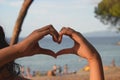 The girl made a shape of heart with her hands. The sea, love, relaxation and enjoyment