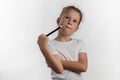 Girl magician with a magic wand in her hands - young magician thinking what to do next - against white background