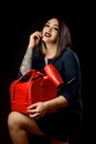 Girl make-up artist in dark dress with red suitcase and accessorized make-up artist