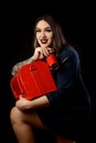 Girl make-up artist in dark dress with red suitcase and accessorized make-up artist