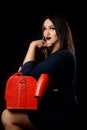 Girl make-up artist in dark dress with red suitcase and accessorized make-up artist