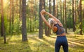 The girl makes bends to the side in the fresh air. The girl performs a warm-up before jogging. Royalty Free Stock Photo