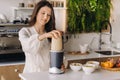 a girl makes a cocktail in a fruit blender in the kitchen. Diet for weight loss