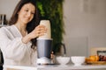 a girl makes a cocktail in a fruit blender in the kitchen. Diet for weight loss