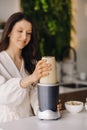 a girl makes a cocktail in a fruit blender in the kitchen. Diet for weight loss