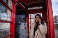 Girl makes a phone call inside a red telephone box in London. Beautiful smiling and attractive woman on the phone Royalty Free Stock Photo