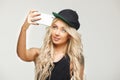 Girl makes selfie on smartphone. gorizontal portrait, view of the phone, self-portrait on isolated white. Royalty Free Stock Photo