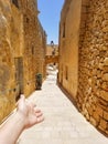 Girl makes a welcome guesture on old narrow street of Victoria, Malta