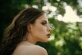 Girl with makeup face, beauty. Woman with long brunette hair on nature. Woman with curly hairstyle and bare shoulder on Royalty Free Stock Photo