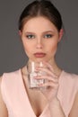 Girl with makeup holding glass of water. Close up. Gray background Royalty Free Stock Photo