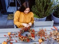 Girl making floral autumn door wreath using colorful rosehip berries, rowan, dry flowers and pumpkins Royalty Free Stock Photo