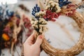 Girl making floral door wreath from colorful dry summer flowers