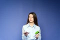 A girl is making online order on the blue background. A girl is recalling a pin