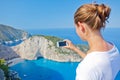 Girl making photo with Navagio bay and Ship Wreck beach in summer. The famous natural landmark of Zakynthos, Greek Royalty Free Stock Photo