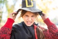 Girl making sinister face with paper black hat