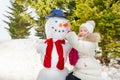 Girl making snowman putting carrot as his nose Royalty Free Stock Photo