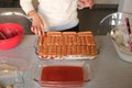 Girl making Strawberry tiramisu. Glass dish with italian savoiardi cookies