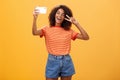 Girl making video vlog with brand new smartphone posting in internet trying become famous standing over orange Royalty Free Stock Photo