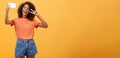 Girl making video vlog with brand new smartphone posting in internet trying become famous standing over orange Royalty Free Stock Photo