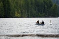 Girl and man with husky dog on kayak with oars in their hands are floating on the waves to go fishing on Lake Merwin with green Royalty Free Stock Photo