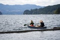 Girl and man with husky dog on kayak with oars in their hands overcame log breakwater on Lake Merwin and go fishing Royalty Free Stock Photo