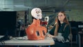 Girl is manipulating robot`s face by means of a computer