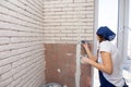 The girl manually plasters imitation of bricks on the wall