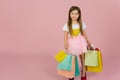 Girl with many shopping bags on pastel pink backgound. Lovely sweet moments of little princess, pretty friendly child having fun Royalty Free Stock Photo