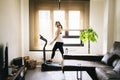 A girl with mask and gloves slim athlete does exercise at home running on the treadmill. Workout