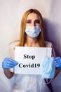 A girl in a mask on her face holds a no Covid19 sign in her hands. The tablet in the hands of a girl on a white background. Blonde Royalty Free Stock Photo