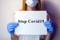 A girl in a mask on her face holds a no Covid19 sign in her hands. The tablet in the hands of a girl on a white background. Blonde Royalty Free Stock Photo