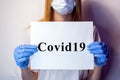 A girl in a mask on her face holds a no Covid19 sign in her hands. The tablet in the hands of a girl on a white background. Blonde Royalty Free Stock Photo