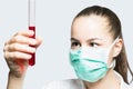 Girl in a mask holding test tube with red liquid - science concept Royalty Free Stock Photo