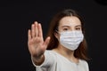 A girl in a mask shows a stop gesture fearing for the health of people