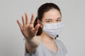A girl in a mask shows a stop gesture fearing for the health of people