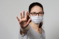 A girl in a mask shows a stop gesture fearing for the health of people