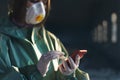 Girl medic in a mask and a protective suit stands in the clinic holds the phone in his hand