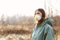 Girl medic in a mask and a protective suit stands on the street