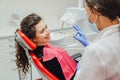 The girl in the medical chair at the dentist smiles grumbling before the treatment. A female doctor in a mask and gloves