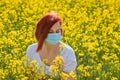 A girl in a medical mask in a field with flowers, protects herself from an allergy to pollen from plants. Coronavirus concept Royalty Free Stock Photo