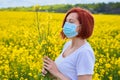 A girl in a medical mask in a field with flowers, protects herself from an allergy to pollen from plants. Coronavirus concept Royalty Free Stock Photo